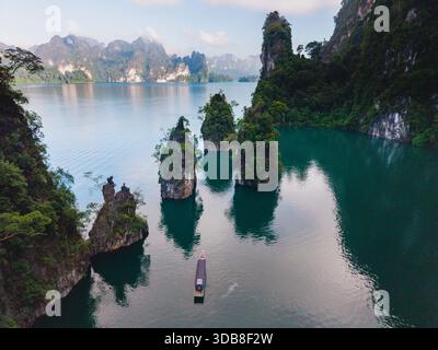 Entdecken Sie die atemberaubende Schönheit des Cheow Lan Lake in Khao Sok, Thailand, wo das ruhige Wasser dramatische Kalksteinklippen reflektiert. Erkunden Sie dieses ruhige Paradies, perfekt für Naturliebhaber. Stockfoto