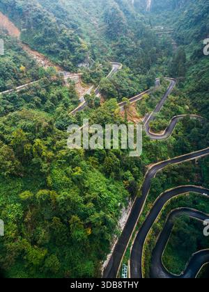 Blick aus der Vogelperspektive auf die gewundene Bergstraße, umgeben von üppigem Grün im Tianmen Mountain, Zhangjiajie National Park in China. Malerische Route mit scharfen Kurven Stockfoto