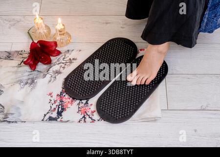 Meditationsbedarf. Yoga Sadhu Board. Frau barfuß stehend auf scharfen Nägeln auf Matte vor brennenden Feuerkerzen geistiges Wachstum geistige Gesundheit. Stockfoto
