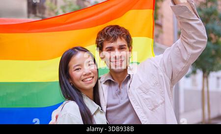 Verschiedene Paare, die lächeln und die Regenbogenflagge feiern Stockfoto