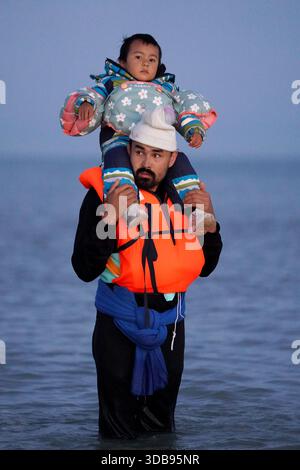 ÜBERPRÜFUNG DER PA FÜR DAS JAHR 2025. Aktenfoto vom 19.09.25: Eine Person, die ein Kind trägt, watet in der Nähe von Gravelines in Frankreich ins Meer. Ausgabedatum: Montag, 15. Dezember 2025. Stockfoto