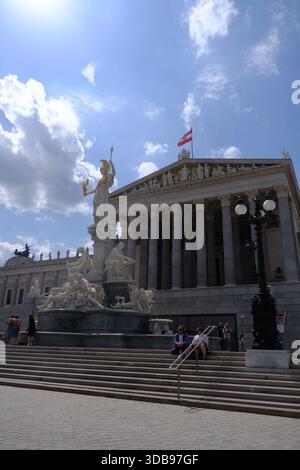 Beeindruckendes österreichisches parlamentsgebäude mit komplizierten Skulpturen und großer Treppe, in Sonnenlicht getaucht. Stockfoto