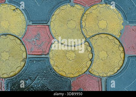 Nahaufnahme von bunten geometrischen Pflasterfliesen, die ein dekoratives, sich wiederholendes Muster bilden. Ziersteinoberfläche mit verwitterter Textur, Stockfoto