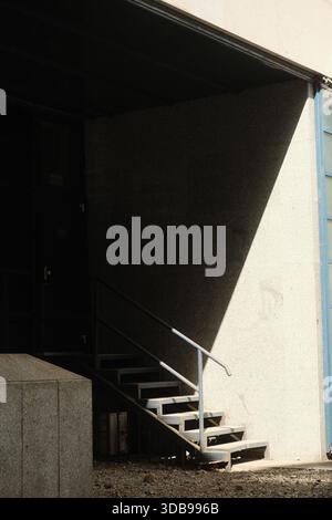 Dramatische Beleuchtung erzeugt starke Schatten auf einer Betontreppe und hebt Textur und architektonische Linien hervor. Eine minimalistische Komposition. Stockfoto