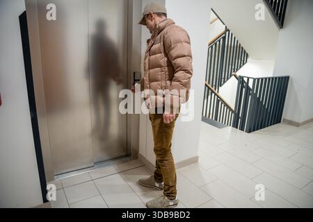 Ein Mann, der durch eine Glastür in ein Wohngebäude eindringt. Tagesablauf in einem Apartmentkomplex. Stockfoto