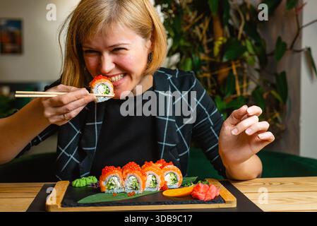 Die Frau beißt während eines entspannten Essens gerne in eine Sushi-Rolle. Stockfoto