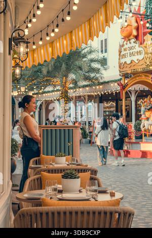 07.12.25 Sunset Toun, Insel Phu Quoc, Vietnam. Straßenfotografie. Eine Frau steht an einem dekorierten Außencafé-Eingang im Phu Quoc Sunset Basar. Stockfoto