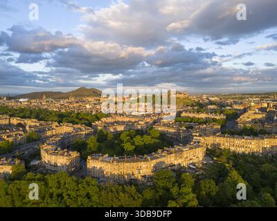 Blick aus der Vogelperspektive auf die sichelförmige georgianische Architektur von Moray Feu, in goldenes Licht getaucht, mit Edinburgh Castle auf einem entfernten Felsen, Mora Stockfoto