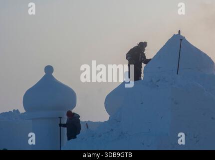 MOHE, CHINA - 15. DEZEMBER 2025 - Schneeskulpturen schnitzen Schneeskulpturen bei extrem kaltem Wetter in Mohe City, Provinz Heilongjiang, China am 15. Dezember 2025. Mohe City, im nördlichsten Teil Chinas gelegen, erlebt extremes Eis- und Nebelwetter, wobei die niedrigste Temperatur an diesem Tag minus 40 Grad Celsius erreicht. Stockfoto