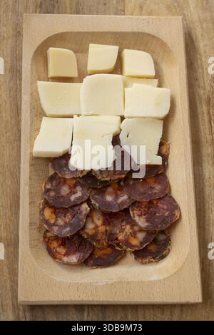Handgemachte Salamischeiben und Käsewürfel auf Holzbrett für Wurstplatte Vorspeise Snack-Zubereitung in rustikaler Küche Stockfoto