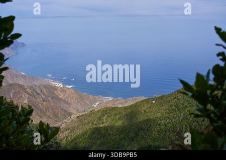 Bergtal, absteigend zur Atlantikküste mit Almaciga Dorf sichtbar am Ufer, eingerahmt von laurisilva Waldvegetation im Anaga Rural Park T Stockfoto