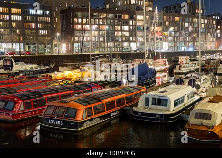 Zahlreiche Boote werden am Abend in einem lebhaften Hafen festgebunden. Die lebhafte Atmosphäre wird durch die farbenfrohen Lichter, die vom Wasser reflektiert werden, verstärkt Stockfoto