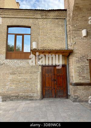 Geschnitzte Holztüren, Fenster an historischer gelb-brauner Ziegelfassade Stockfoto
