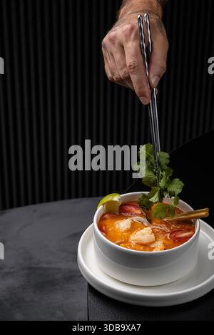 Der Koch verwendet Essstäbchen, um das Gemüse in tom Yamssuppe isoliert zu geben Stockfoto
