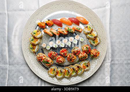Großes Sushi-Set auf einem schönen Teller auf einem hellen Hintergrund isoliert Stockfoto