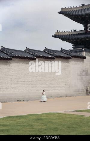 Eine Frau mit traditionellem Hanbok, die außerhalb von Gyeonbokgung läuft Stockfoto