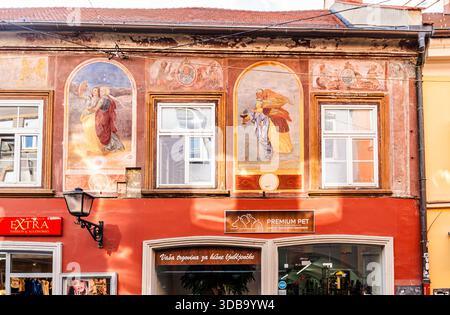 Fresken mit eleganten weiblichen Figuren in einem Wohngebäude mit roter Fassade in Gosposka ulica, dem historischen Stadtzentrum von Maribor, Slowenien. Stockfoto