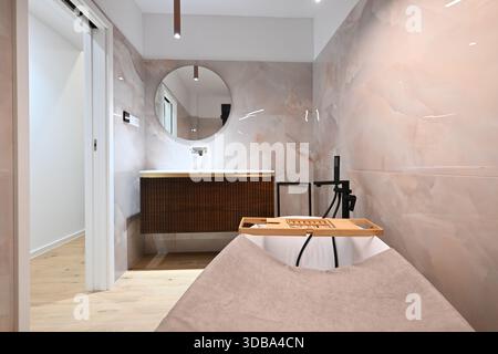Luxuriöses, modernes Badezimmer mit eleganter freistehender Badewanne mit Caddy, elegantem Kosmetikbereich mit Waschbecken und Spiegel und moderner Toilette. Weich Stockfoto