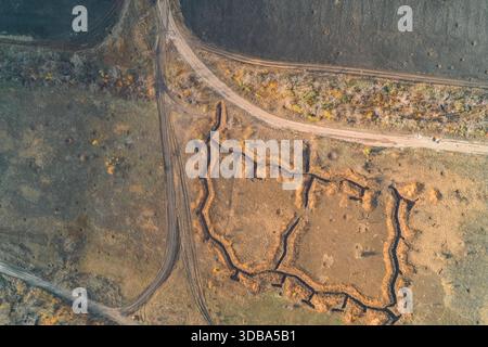 Von oben nach unten auf einen Verteidigungsstützpunkt des Zuges mit einem komplexen Netz von Erdgräben. Die komplizierte Festungsanlage im offenen Feld hebt die Militärtechnik in der Konfliktzone hervor. Stockfoto