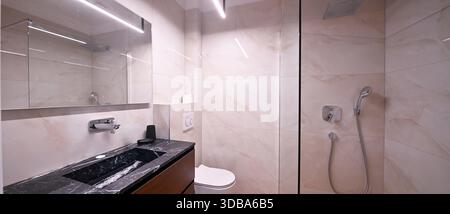 Luxuriöses, modernes Badezimmer mit eleganter freistehender Badewanne mit Caddy, elegantem Kosmetikbereich mit Waschbecken und Spiegel und moderner Toilette. Weich Stockfoto