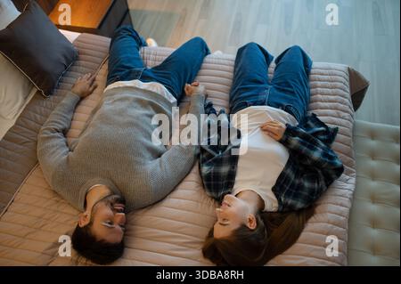 Ein junges Paar liegt auf dem Bett in einem Hotelzimmer und fühlt sich entspannt Stockfoto