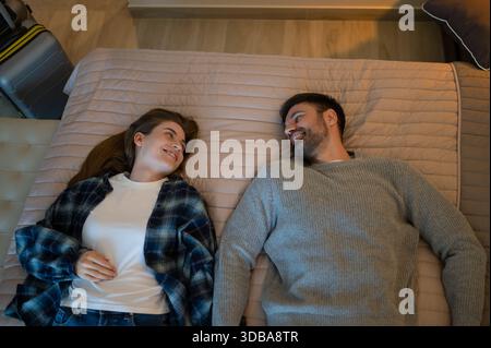 Ein junges Paar liegt auf dem Bett in einem Hotelzimmer und fühlt sich entspannt Stockfoto