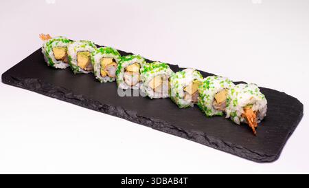 Uramaki Sushi-Rollen mit Garnelentempura, Avocado und grünem Tobiko serviert auf schwarzem Schieferteller isoliert auf weißem Hintergrund. Stockfoto