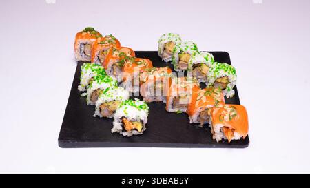 Verschiedene Sushi-Brötchen mit Lachs und Avocado serviert auf schwarzem Schieferbrett isoliert auf weißem Hintergrund. Stockfoto