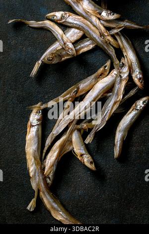 Haufen getrockneter, sonnengetrockneter Meeresfische riechen hamsa-Sardellen auf dunklem, strukturiertem Hintergrund. Salzige Vorspeise. Meeresfrüchte-Hintergrund Stockfoto