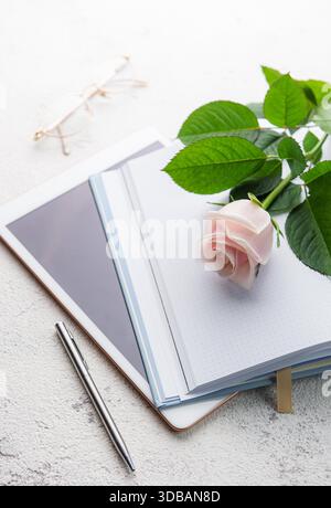 Flach liegender Büroschreibtisch für Frauen. Weiblicher Arbeitsplatz mit pinkfarbenem Blumenstrauß, Milchprodukte, Gläser Stockfoto