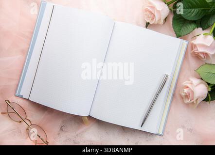 Flach liegender Büroschreibtisch für Frauen. Weiblicher Arbeitsplatz mit pinkfarbenem Blumenstrauß, Milchprodukte, Gläser Stockfoto