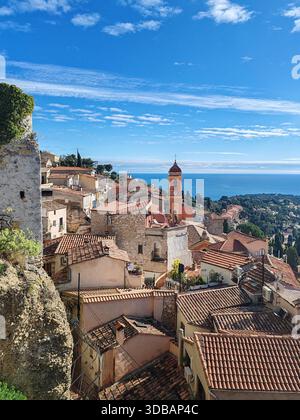 Panoramablick auf das auf einem Hügel gelegene Dorf Roquebrune Cap Martin mit Terrakottadächern, Kirchturm und dem Mittelmeer unter einem hellblauen Winterhimmel Stockfoto