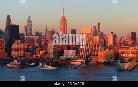 New York City aus der Vogelperspektive auf die Wolkenkratzer von Midtown Manhattan, die von warmen Sonnenstrahlen beleuchtet werden. Chelsea Uferpromenade und Hudson River Stockfoto