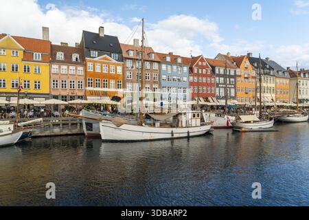Kopenhagen, Dänemark - 30. September 2025: Blick auf Nyhavns ikonische Uferpromenade, wo lebendige Gebäude auf den ruhigen Kanal treffen und den klaren Himmel reflektieren Stockfoto
