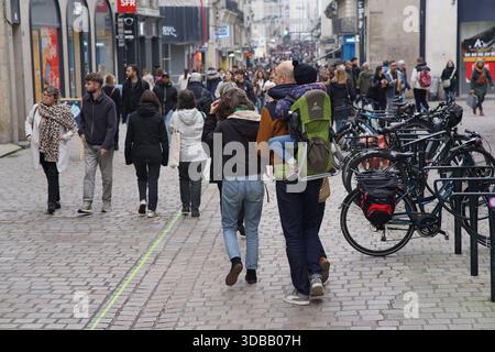 Menschen, die an einem bewölkten Tag in einer belebten Fußgängerzone in einem europäischen Stadtzentrum spazieren, mit Fahrrädern in der Nähe. Nantes, Frankreich Stockfoto