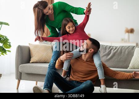 Glückliche arabische Familie, die am Wochenende verspielte Momente in ihrem Wohnzimmer genießt Stockfoto
