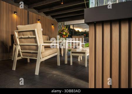 Stühle und Tisch stehen in einem schattigen Raum neben Pflanzen und Blumen, wodurch ein Treffpunkt im Freien geschaffen wird. Stockfoto
