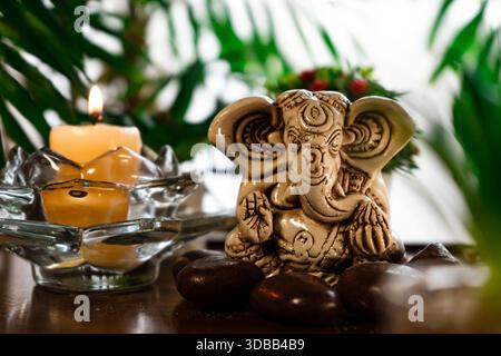Ein Vermittlungsaltar, der Ganesha gewidmet ist, mit einer kleinen Figur, Kerzen, einigen Pflanzen und Weihrauch. Stockfoto