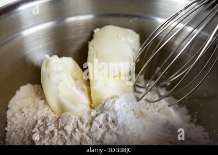 Das feste Gemüsekürzen wird in einer silbernen Schüssel mit einem Schneebesen in die trockene Mehlmischung geschnitten, ein wichtiger Schritt für die Herstellung von leichten und flauschigen Waffeln in Waukesh Stockfoto