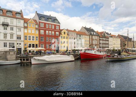 Blick auf farbenfrohe Gebäude am Kanalrand, wo Boote im lebhaften Hafen Nyhavn, Kopenhagen, Dänemark, auf dem Wasser schweben. Stockfoto