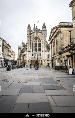 Der Blick auf die große Kathedrale erhebt sich majestätisch über dem weitläufigen Steinplatz und wirft lange Schatten im gedämpften Licht, Wells, England, Vereinigtes Königreich Stockfoto