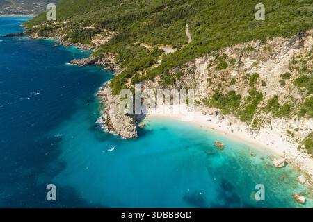 Aus der Vogelperspektive auf türkisfarbenes Wasser, das die zerklüftete Küste und Sandstrände unter grünen Klippen umschließt, Lefkada, Lefkada, Griechenland. Stockfoto