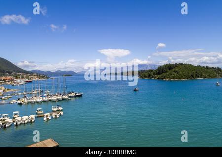 Aus der Vogelperspektive auf das unberührte türkisfarbene Wasser umgibt den Hafen mit seinen eleganten weißen Yachten, im Kontrast zur grünen Küste, Nydri, Lefkada, Gr Stockfoto