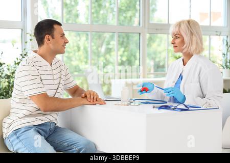 Endokrinologin zeigt Schilddrüsenmodell beim Mann in der Klinik Stockfoto