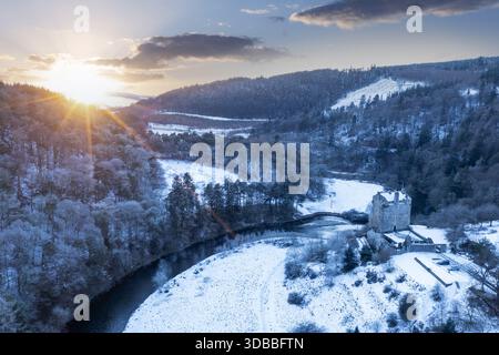 Aus der Vogelperspektive von Neidpath Castle inmitten einer schneebedeckten Landschaft, mit dem Fluss Tweed, der sich durch das frostige Gelände unter dem Glanz der Wintersonne schlängelt., PE Stockfoto