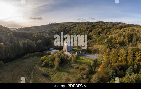 Blick aus der Vogelperspektive auf das historische Neidpath Castle, das stolz inmitten der herbstlichen Farbtöne des umliegenden Waldes steht, wo sich der Fluss Tweed ruhig schlängelt Stockfoto