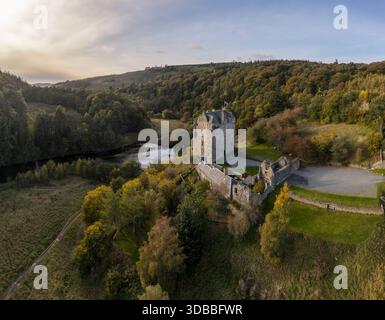 Blick aus der Vogelperspektive auf das historische Neidpath Castle, das stolz auf einem Hügel steht, umgeben von lebhaftem Herbstlaub mit dem Fluss Tweed, der sich in der Nähe schlängelt, Peeb Stockfoto