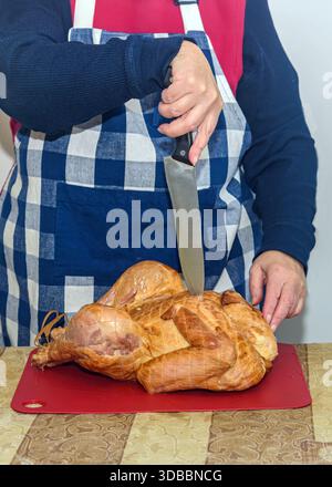 Eine Frau bereitet den geräucherten truthahn für den festlichen Tisch vor. Stockfoto