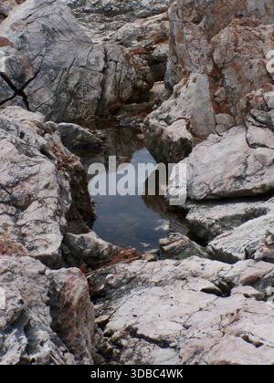 Abwechslungsreiche Kalksteinformationen mit einem kleinen Teich in der Mitte an der Adria Stockfoto