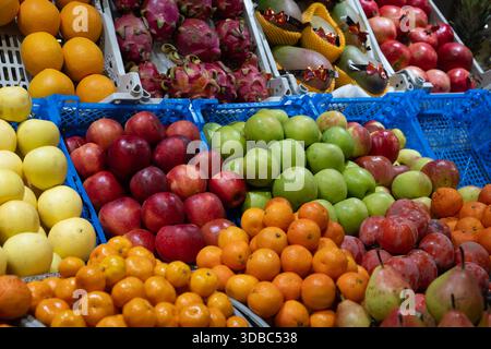 Lebendige, exotische Obstmärkte: Rote und grüne Äpfel, Orangen, Mandarinen, Persimmonen, Birnen, drachenfrucht, Mangos und Granatäpfel angeordnet. Stockfoto
